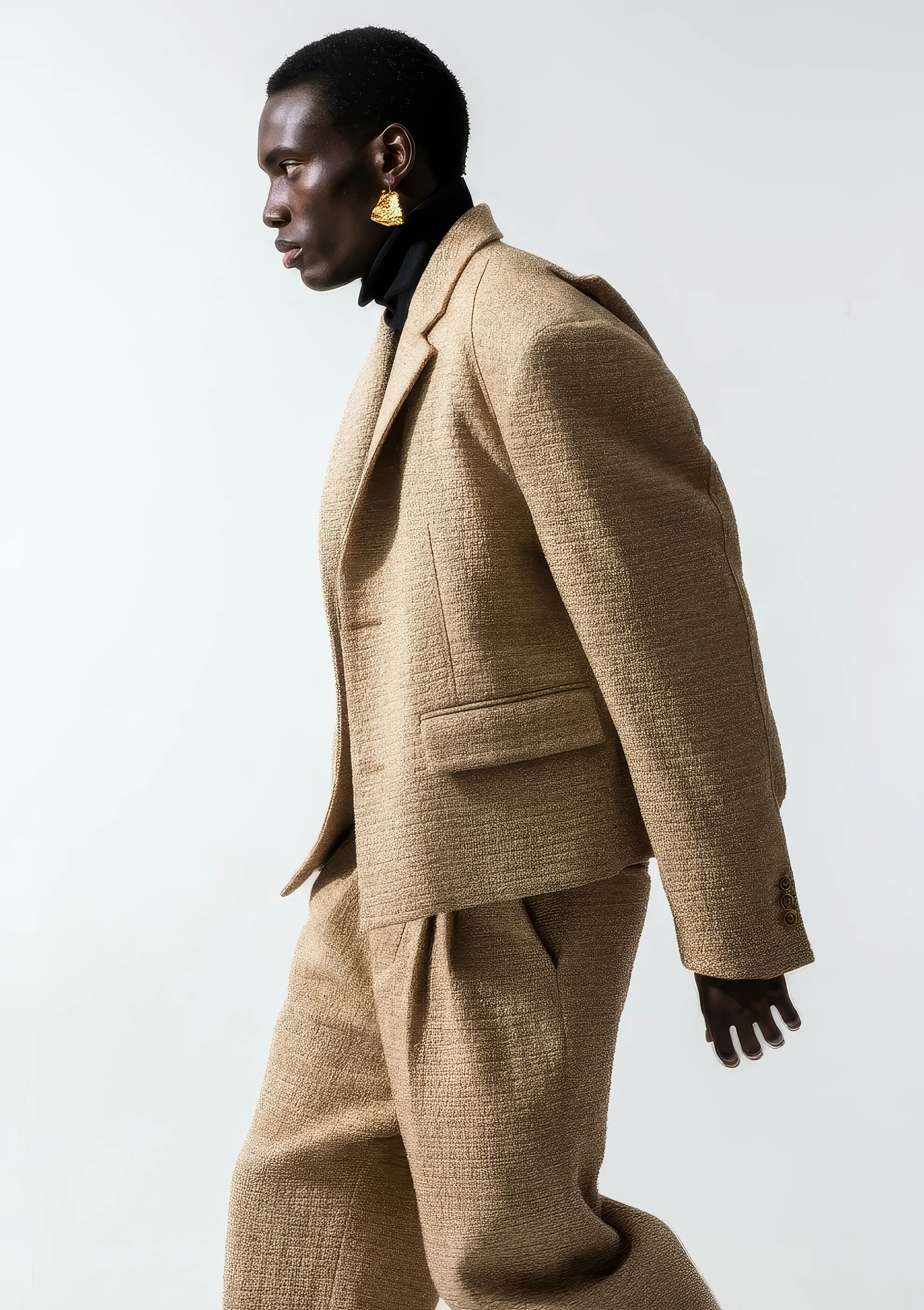 Model walking in a camel textured power suit with a gold earring